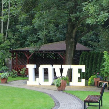 Napis LOVE pod altaną w ogrodzie